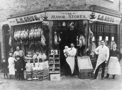 G. H. Grigg, the Manor Stores
Wholesale and retail. Poultry and an animal carcase on display for sale. Large (display?) drum of Birds custard, several cubical biscuit boxes. Shop staff and family(?).
Keywords: shops