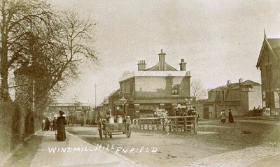 Windmill Hill in 1906
A view looking East down Windmill Hill, Enfield Chase in 1906 showing:
1. The forecourt of the old Enfield (G.N.R.) Terminus – Right.
2. The Windmill Public House – Centre.
3. The new bridge erected ready to take the Cuffley extension over Windmill Hill but with the associated earth embankment not yet constructed – Far distance.
Keywords: rail transport;pubs