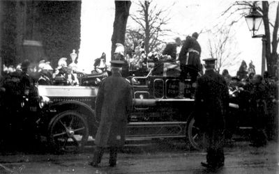 Fireman's funeral
Fire engine with wording "Enfield U.D.C. / Ponders End" appears to have a coffin on top, covered with a union flag and flowers. Firemen in background with brass Roman helmets. A postcard, with notes on back reading "Possibly members of Coats(?) family of 84 Nags Head Road, or, Chief Officer Richard Walter, Ponders End Fire Brigade, 1880-1922". It is possibly the funeral in August 1932 of Capt. Edwin T. Roberts of the Ponders End brigade. Another photograph of this event is in [i]History of Enfield[/i] vol.3, p.170.
Keywords: funerals;fire engines;firemen;events