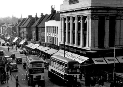 Enfield Town, looking northwest along Church Street
Burton's building prominent at the corner of the marketplace. Buses, cars and many people on the pavement. Two-way traffic on Church Street.
Keywords: cars;roads and streets;shops;buses