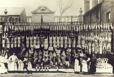 A. H. Clarke, family butcher. Meat and poultry display.
Location unknown. They had a shop at 109 Ordnance Road, Enfield and in 1939-1943 they traded at 145 High Street, Waltham Cross. This appears to be a special display, but the occasion is not known. A postcard copy of the image is postmarked 2nd May 1907, so it must date from earlier than that.

Though eight staff are in attendance, there is no counter visible at which meat could be prepared or sold. Can anyone identify the location from the architecture behind the display?

Labels on the meat read "Prime Scotch beef", "Choice Southdown mutton", "Fed by ... Earl of Rosebery ..."
Keywords: 1900s;butchers;retail