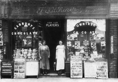 F. Kitchener, tobacconist and confectioner
Location unknown. Daily Herald poster reads "Labour exposes cabinet bungling". Confectionary window advertises "Mars - the health food"; "Fry's blocks" cost 2d. each. The slot machine at the right sells "Beech Nut peppermint chewing gum" at 2 pieces for 1d.  
Keywords: shops;retail