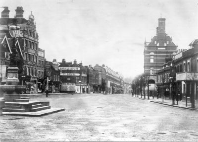 The Town, looking west
On the left, beyond the George Inn, is Enfield House, advertised as "Wm. LOCK, GENERAL DRAPER". This business was taken over by Pearson Brothers in May 1902, but Wm. Lock's name remains in another picture dated 1908. Barclays Bank, on the right, was opened in 1898. The round lamp on top of the fountain may help to date the picture.
Keywords: 1900s;banks;roads and streets;shops;fountains