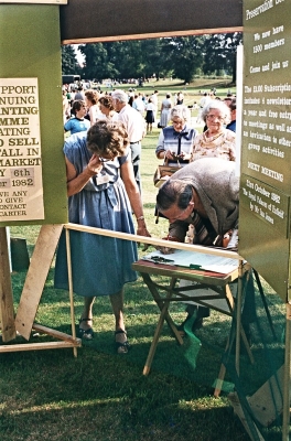Autumn show, Town Park, 1982
Valerie Carter watching Donald Potter signing a paper. The display panel reads "Enfield Preservation Society / We now have 1500 members / Come and join us / The £1.00 subscription includes 4 newsletters a year and free entry to meetings as well as an invitation to other group activities
 / NEXT MEETING / 21st October 1982 / The Royal Palaces of Enfield by Mr Ian Jones"
Keywords: 1980s;Enfield Preservation Society;EPS;exhibitions;Town Show