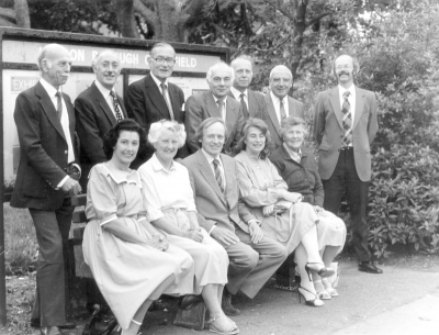 Enfield Preservation Society council of management, 1984
On the Library Green. The front row are sitting on the seat recently installed by EPS in memory of Reg Williams, a vice-president.
[i]Sitting (left to right):[/i]Irene Smith, Priscilla Lowen, Christopher Jephcott,  Hilary Stone, Velma Byford. [i]Standing:[/i]Stan Lowen, Gordon Macfarlane, Donald Potter (President), Alan Skilton, Derek Needham, Wally Woodfield, Stuart Mills.
[i]Missing[/i] from the picture are the remaining member of the COM for 1985/85: Valerie Carter, Denis Hoy, Len Keeble, Pam Mills, David Pam and Derek Stone
Keywords: 1980s;Enfield Preservation Society;EPS;seats;memorials