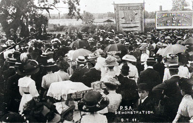 PSA gathering, July 1911
The PSA (Pleasant Sunday Afternoon) movement  was founded by John Blackham, a deacon of Ebeneezer Congregational church, West Bromwich to provide a little relief in the Midlands by providing a regular non-denominational Sunday afternoon meeting with something of interest. The meetings were to be "Brief, Bright and Brotherly", and became a 'brotherhood'. The image is labelled "P.S.A. demonstration", but it appears to be be a peaceful meeting with men and women in hats and a pram in the foreground. The image is in [i]History of Enfield[/i] vol.2, p.333.
Keywords: 1910s;events;people;banners