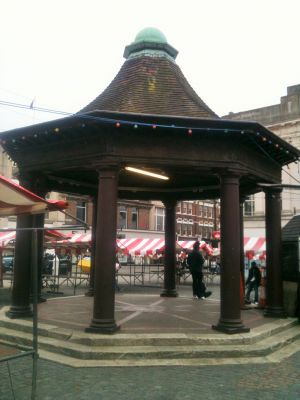 The Town. Market House.
Built in 1904 to replace the dilapidated market cross. An octagonal structure supported by eight columns of teak raised by public subscription from a design by the late Mr Sidney W. Cranfield. The roof is covered with hand-made tiles and terminated in a copper dome. Upon the cornice beneath the roof is inscribed [i]"This Market House was erected by subscription to commemorate the coronation of Kind Edward VII. Dei. Gra. Omn. Rex Fid. Def. Ind. Imp."[/i] It is somewhat similar in style to the Old Market House demolished in 1826. - [i]History of the Enfield Parochial Charity / Robert H. Dugdale Sykes, 1988, page 14.[/i] 
Keywords: locally listed;The Town;market places